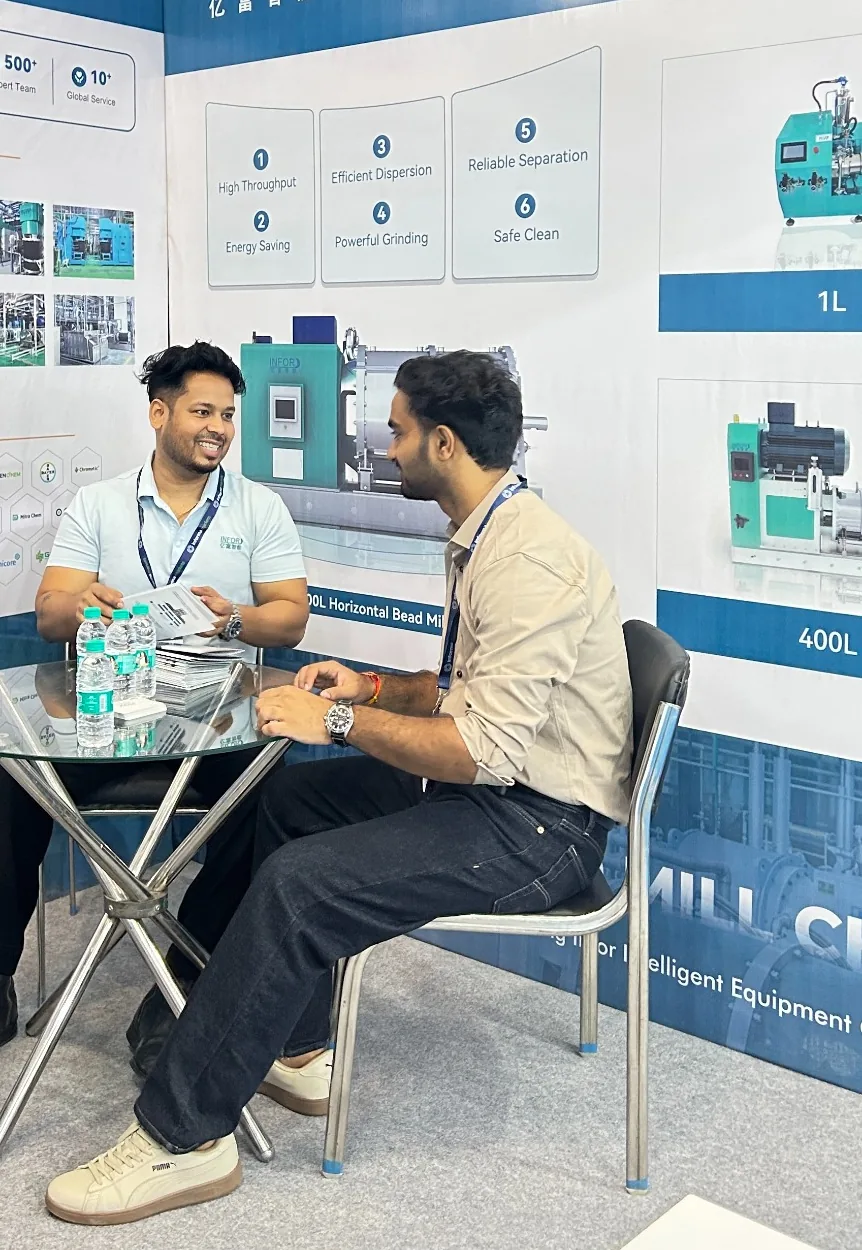 An INFOR team member discussing a grinding project with a visitor at the booth